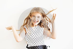 Lovely frisky little girl in a polka-dot dress against a white b