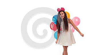 Lovely girl brunette with long hair in a white dress with a bow on her head and balloons posing on a white background