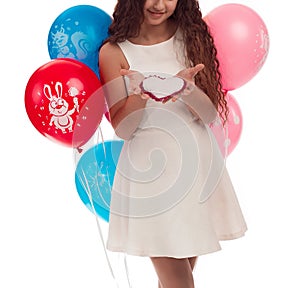 Lovely girl brunette with long hair in a white dress with a bow on her head and balloons posing on a white background