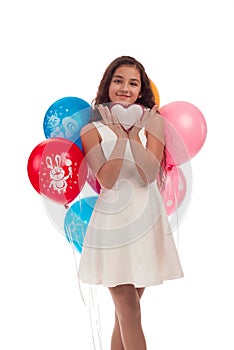 Lovely girl brunette with long hair in a white dress with a bow on her head and balloons posing on a white background