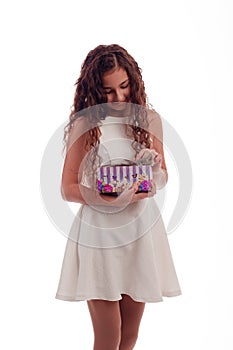 Lovely girl brunette with long hair in a white dress with a small gray kitten in a gift box in his hands on a white background in