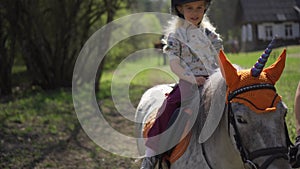 Lovely girl child ride unicorn pony horse. Gimbal stabilizer movement shot