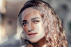 Lovely girl close-up portrait, face lit by ray of sunshine, contrasting photo