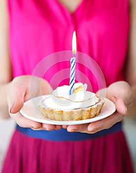 Lovely girl holding in hands cupcake with one candle. Birthday p