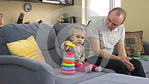 Lovely girl and loving father play colorful pyramid rings. Man commend daughter