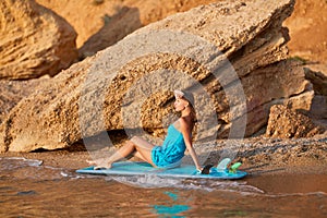 Lovely girl with perfect figure posing on surfboard at sea beach. Summer vibes, summertime and active lifestyle concept