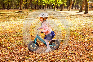 Lovely girl riding balance bike in atumn park