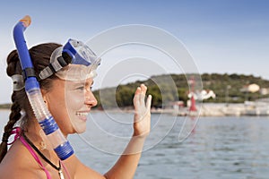 Lovely girl at the seaside wearing a diving mask and waving hello