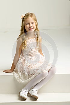 Lovely girl sitting on white staircase. Studio portrait.