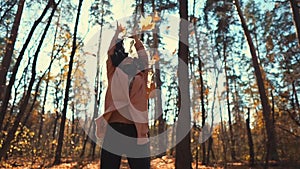 Lovely girl throwing leaves in autumn.