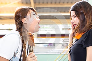 Lovely girl is using hand close her nose because her friend persecute and blow her bad breath to her. She eat some stink food. Pr photo