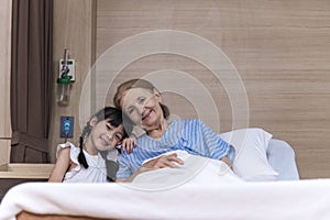 Lovely girl visit and encourage grandmother on patient bed in hospital