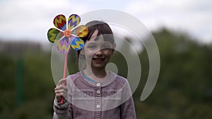 Lovely girl with windmill toy on the nature smiling and looking at the camera