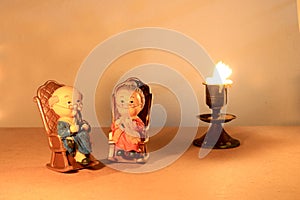 Lovely grandparent doll siting classic chair design and candle with light candle tone. low key lighting, still life style.