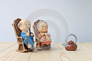 Lovely grandparent doll siting old sofa classic chair together on wooden table with background.