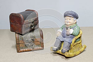 Lovely grandparent doll siting rocking bamboo chair on wood background. -still life.