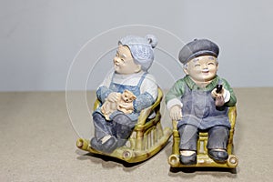 Lovely grandparent doll siting rocking bamboo chair on wood background. -still life.