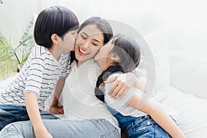 Lovely happy Asian family at cozy home. Son and daughter kiss mother with enjoy ,relax and playful together in bedroom. Happiness