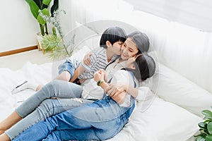 Lovely happy Asian family at cozy home. Son and daughter kiss mother with enjoy ,relax and playful together in bedroom. Happiness