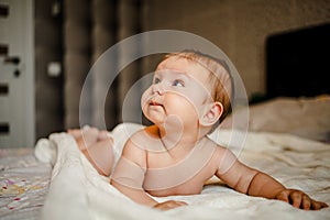 Lovely Happy Baby With Surprised Blue Eyes Close-up. Infant Playing Home On Bed In Morning.