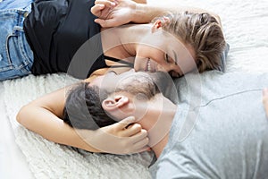 Lovely happy couple in love, smile, and kiss each other on their bed in the bedroom