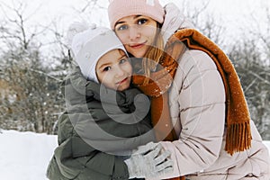 Lovely happy family mother and little girl daughter having fun on snowy weather outdoors