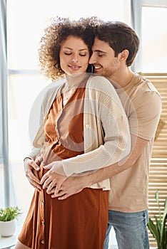 Lovely happy man hugging his pregnant