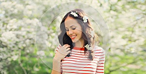 Lovely happy smiling young woman in spring blooming garden with white flowers on the trees in park