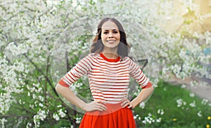 Lovely happy smiling young woman in spring blooming garden with white flowers on the trees in park