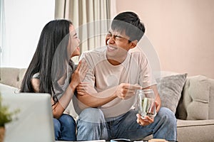 A lovely, happy young Asian new married couple is planning their savings together in the living room