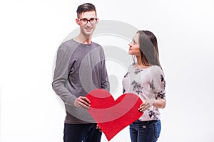 Lovely hipster couple with a red heart in hands. Man look at camera, girl look at man.