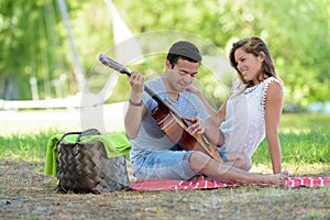 lovely interracial couple sitting with guitar in park photo