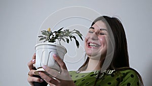 A lovely lady caring for potted plants at home, spraying water with a spray gun smiling at home. People and floristry