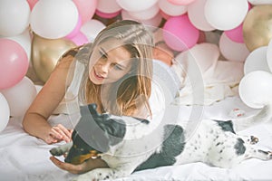 Lovely lady in pajama in bedroom play with her dog. Indoor portrait  girl with baloons in morning. Husband surprising his wife