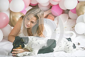 Lovely lady in pajama in bedroom play with her dog. Indoor portrait  girl with baloons in morning. Husband surprising his wife