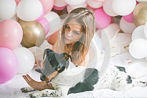 Lovely lady in pajama in bedroom play with her dog. Indoor portrait  girl with baloons in morning. Husband surprising his wife