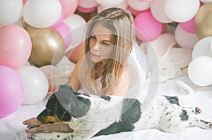 Lovely lady in pajama in bedroom play with her dog. Indoor portrait  girl with baloons in morning. Husband surprising his wife