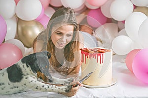 Lovely lady in pajama making selfie in her bedroom using phone with her dog. Indoor portrait  girl with baloons in morning.