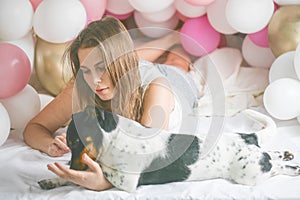 Lovely lady in pajama making selfie in her bedroom using phone with her dog. Indoor portrait  girl with baloons in morning.