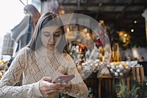 A lovely lady with a phone explores the offerings of the decor shop.