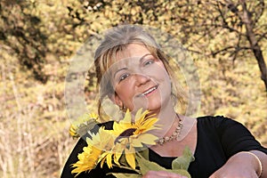 Lovely lady poses outdoors holding sunflowers