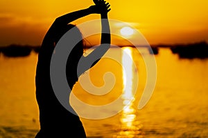 A Lovely Latin Model Is Silhouetted As She Poses With The Rising Sun Behind Her On A Romantic Caribbean Beach