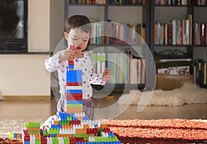 Lovely laughing little child, brunette girl of preschool age playing with colorful blocks sitting on a floor