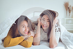 Lovely lesbian couple together concept. Couple of young women lying under blanket after wake up with happiness moment.