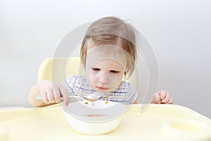 Lovely little 2 years girl eating soup at home kitchen