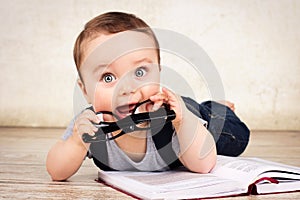 Lovely little baby boy with glasses reading a book