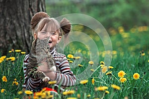 Lovely little five-year girl and cat in green grass.