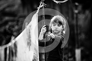 Lovely little five-year girl with clothespin and the clothesline. Black and white photo.