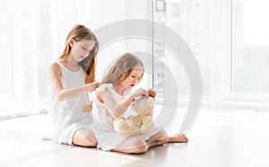 Lovely little girl brushing hair of younger sister