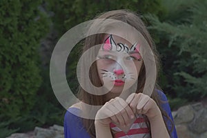 A lovely little girl with the paint on her face. Girl with a painted cat on her face. Children of the Z-generation